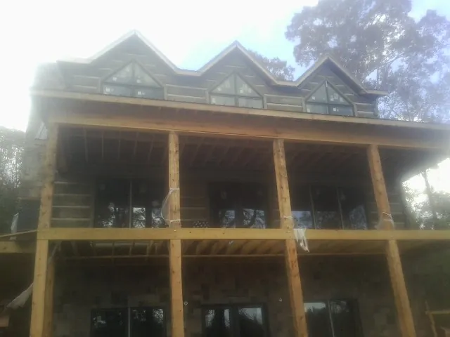 Dormers and porch framing on a large log home under construction — Roof Coating work by our crew in Westpoint