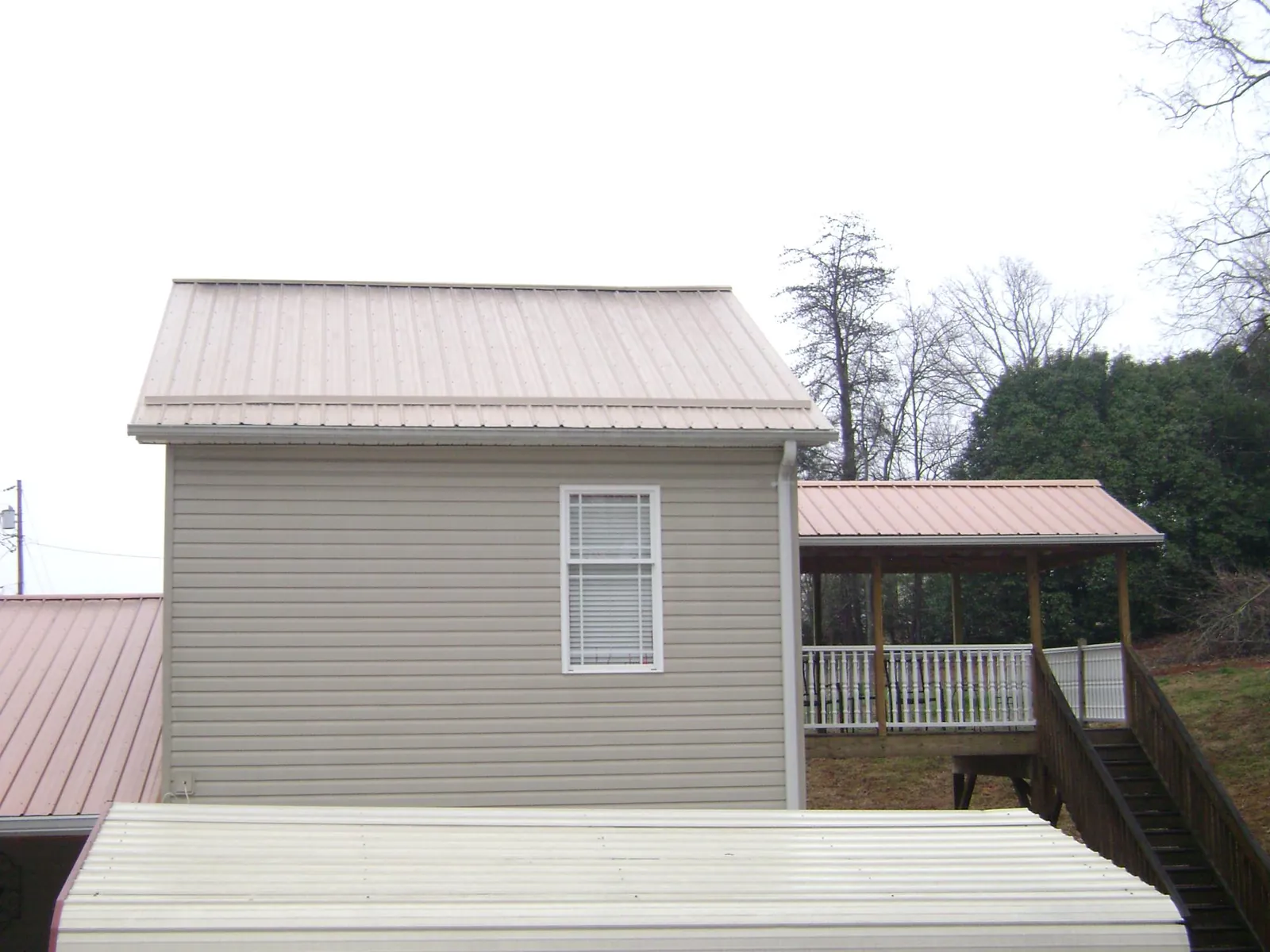 Tan metal roofs on a two story addition and attached porch, from a Roof Replacement job in Westpoint