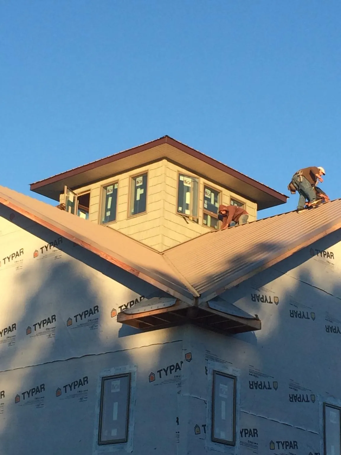 Roofers working around a rooftop cupola on a new metal roof at sunset — Roof Waterproofing in Westpoint by Roofing Brothers